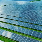 Solar power station in the green field. Blue sky and clouds are reflected on the photovoltaic panel. Production of solar energy
